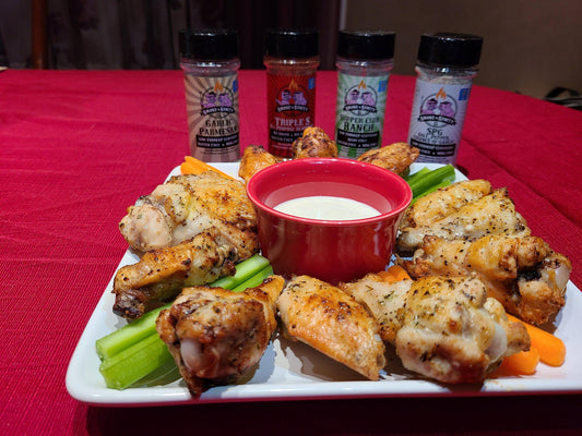 Plate of cooked chicken wings with a dish of sauce celery and carrots