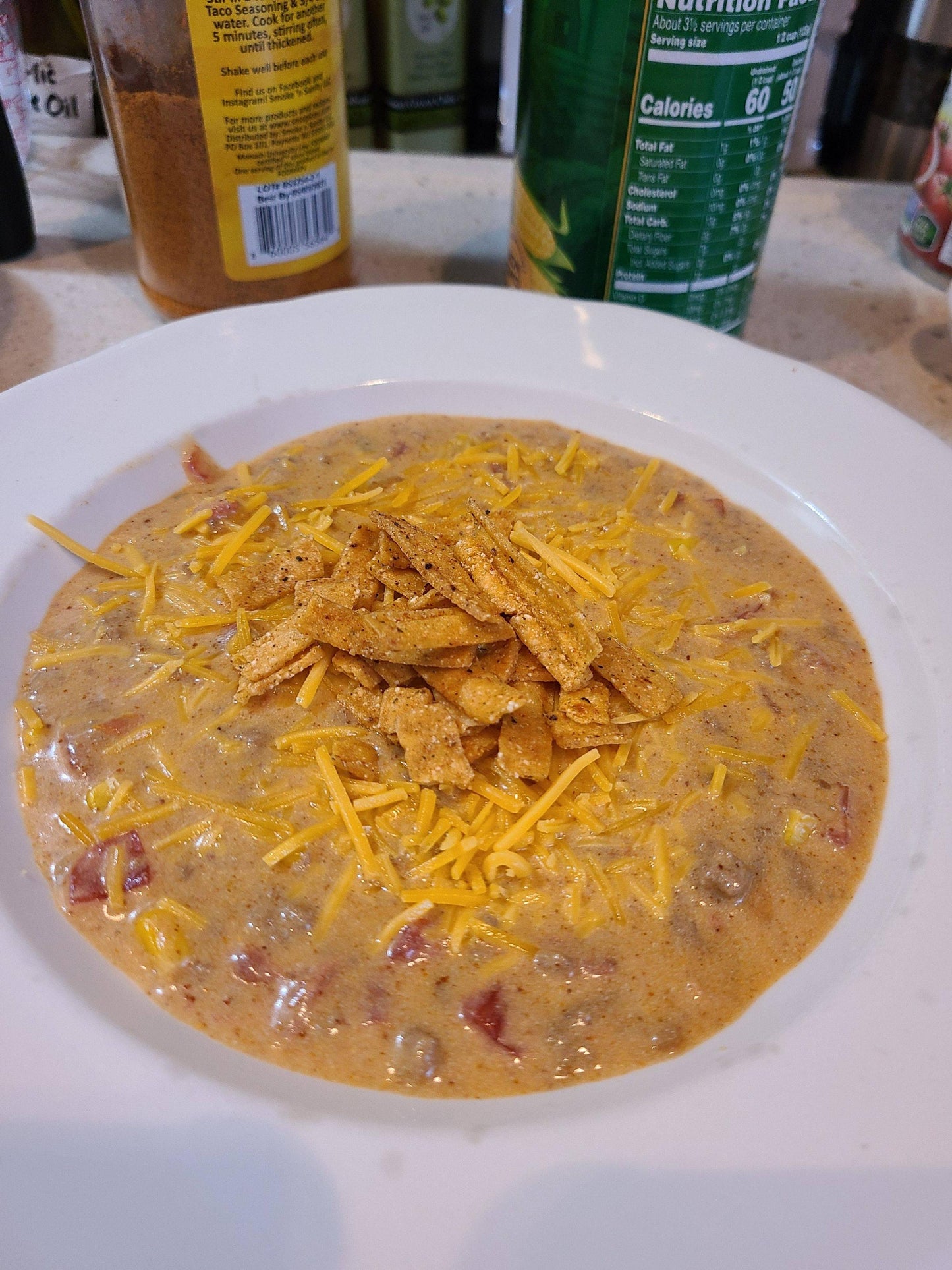 Bowl of enchilada taco soup topped with cheese and tortilla chips