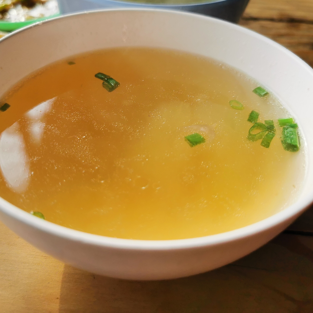 Bowl of beef broth with diced green onion